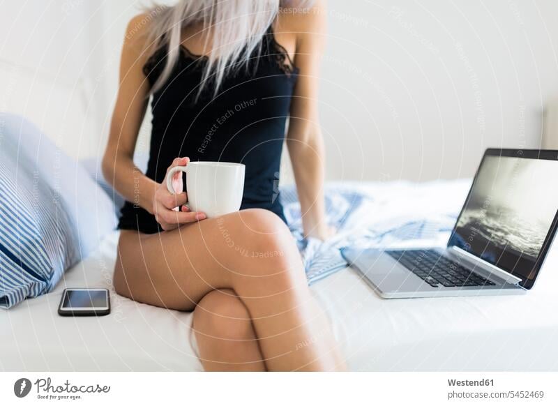 Young woman in bed with cup of coffee and laptop Coffee Laptop Computers laptops notebook Coffee Cup Coffee Cups females women beds Drink beverages Drinks
