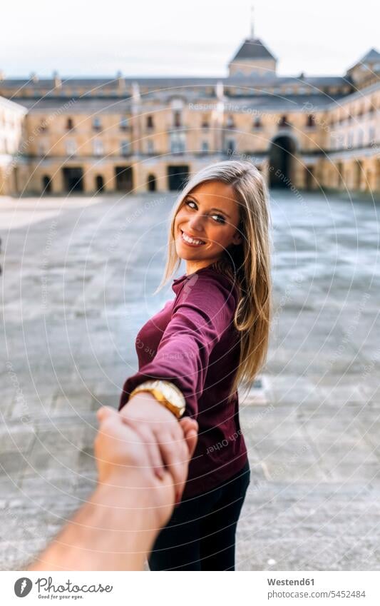 Happy young woman holding hand on urban square smiling smile females women couple twosomes partnership couples Adults grown-ups grownups adult people persons