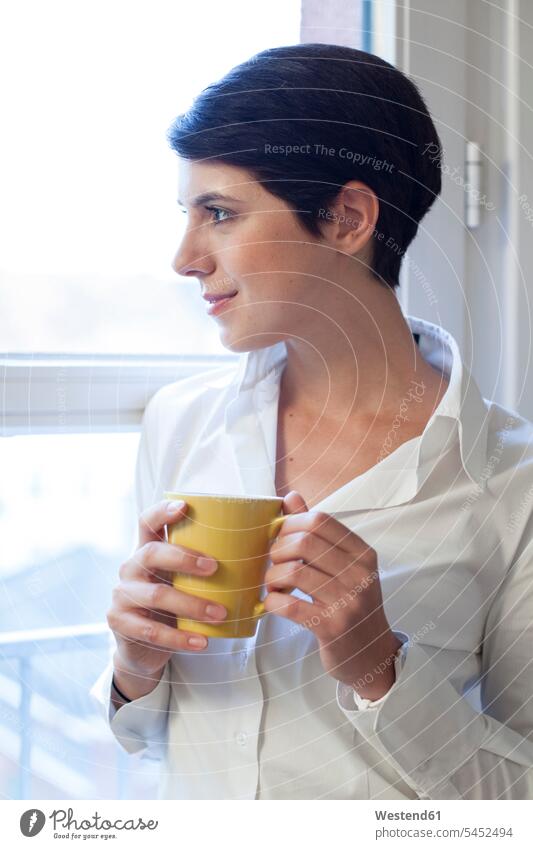 Woman holding cup of coffee looking out of window smiling smile Coffee woman females women windows Drink beverages Drinks Beverage food and drink Nutrition