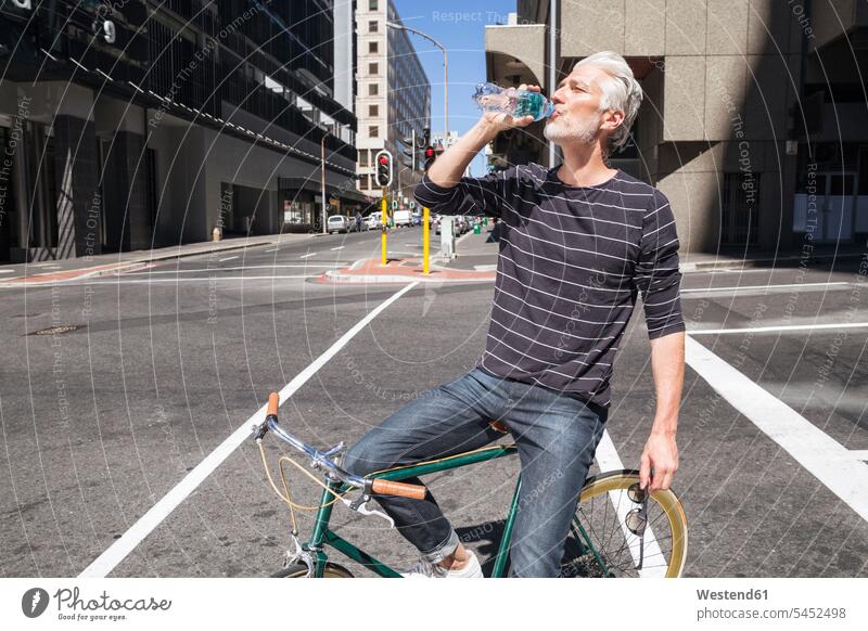 Man on bicycle drinking water city town cities towns on the move on the way on the go on the road bikes bicycles riding bicycle riding bike bike riding cycling