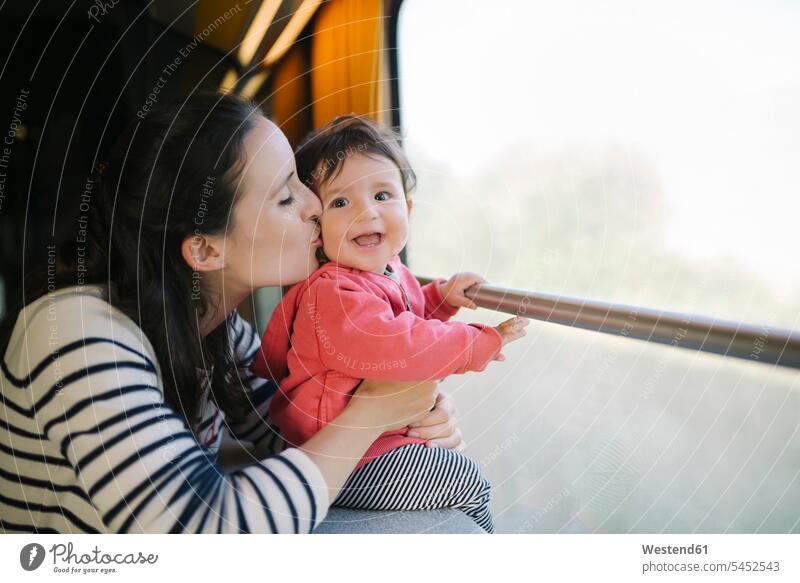 Happy mother and baby girl traveling by train infants nurselings babies laughing Laughter mommy mothers ma mummy mama travelling kissing kisses people persons