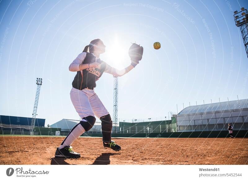 Female baseball player catching the ball during a baseball game games woman females women sport sports Adults grown-ups grownups adult people persons