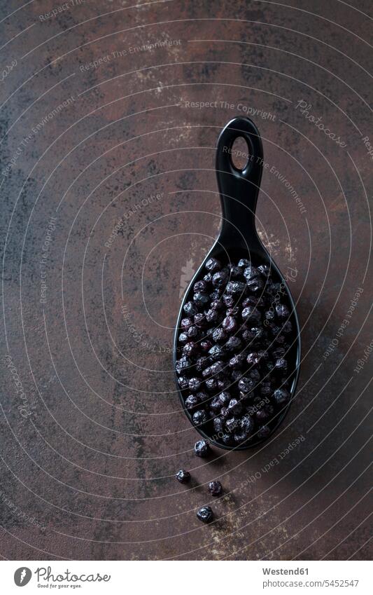 Spoon of dried chokeberries on rusty metal black gleaming dried fruit Dried Fruits dark background superfood spoon spoons chokeberry Aronia healthy eating