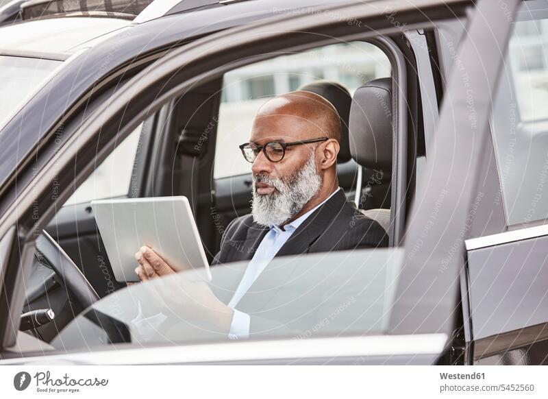 Businessman sitting in car using digital tablet digitizer Tablet Computer Tablet PC Tablet Computers iPad Digital Tablet digital tablets on the move on the way