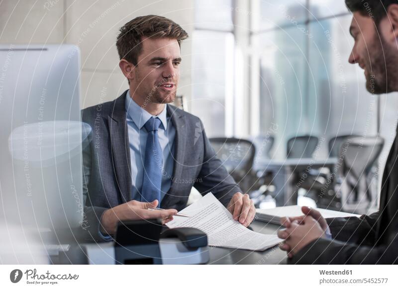 Businessman talking to client in office document paper documents papers contract contracts Business man Businessmen Business men business people businesspeople