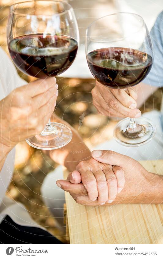 Close-up of senior couple having glass of red wine and holding hands outdoors human hand human hands twosomes partnership couples Wine people persons