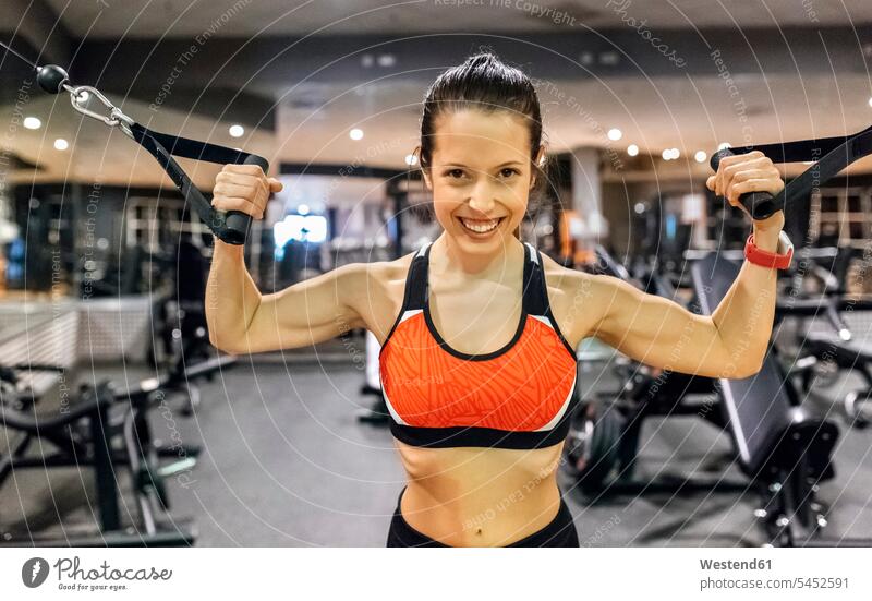 Portrait of a happy young woman working out in gym exercising exercise training practising females women gyms Health Club smiling smile Adults grown-ups