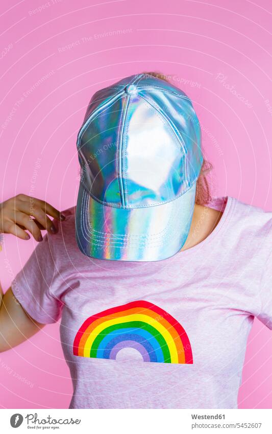 Young woman with headphones hiding her face behind basecap in front of pink background baseball cap visor cap peaked cap visored cap baseball caps baseball hat