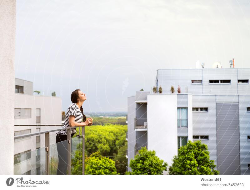 Woman with cup of coffee standing on balcony roof terrace deck rooftop woman females women Adults grown-ups grownups adult people persons human being humans