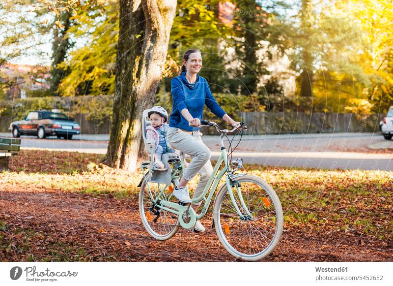 Mother and daughter riding bicycle, baby wearing helmet sitting in children's seat bikes bicycles laughing Laughter Child's Seat child seat child safety seat