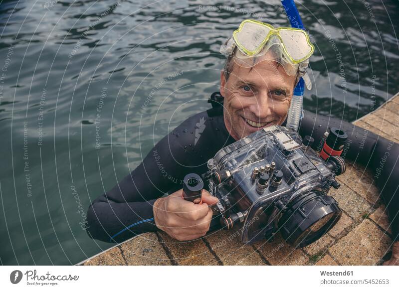 Portrait of happy man with underwater DSLR camera case in water cameras diving dive smiling smile men males diver divers Adults grown-ups grownups adult people