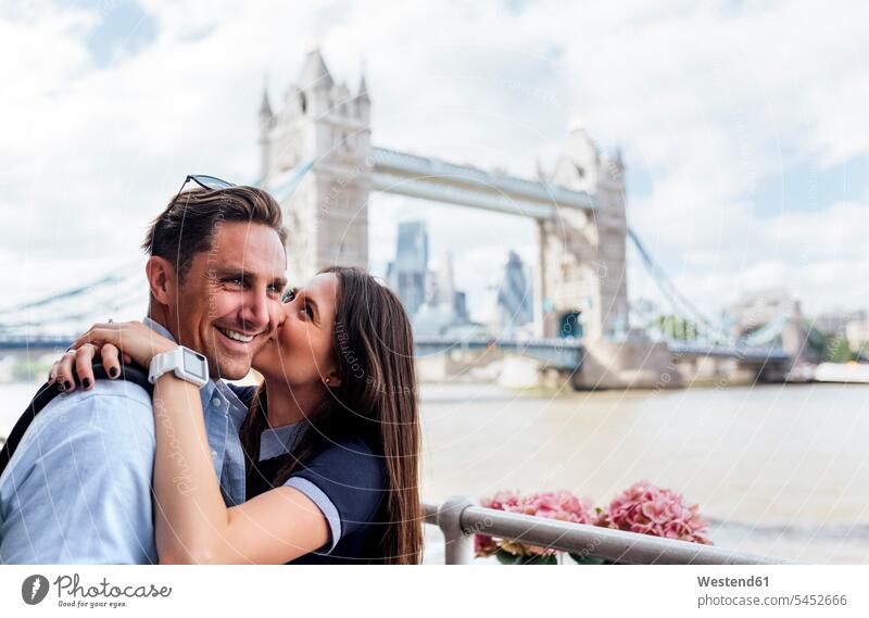 UK, London, happy couple kissing with the Tower Bridge in the background kisses smiling smile embracing embrace Embracement hug hugging twosomes partnership