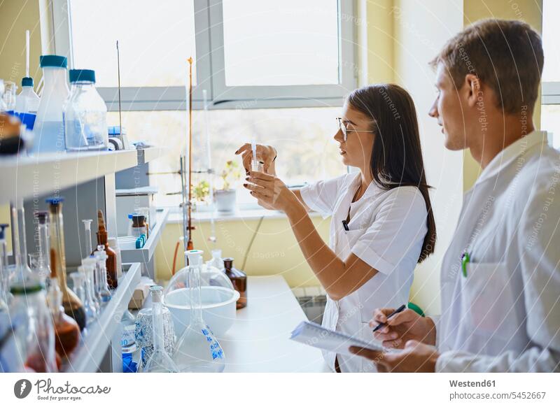 Young man and woman working together in laboratory females women At Work Adults grown-ups grownups adult people persons human being humans human beings