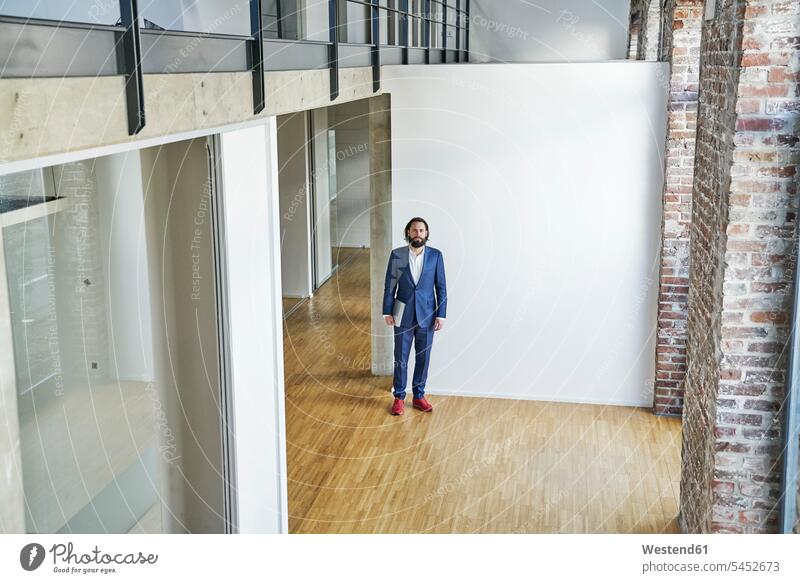 Portrait of businessman standing on empty office floor offices office room office rooms Businessman Business man Businessmen Business men workplace work place