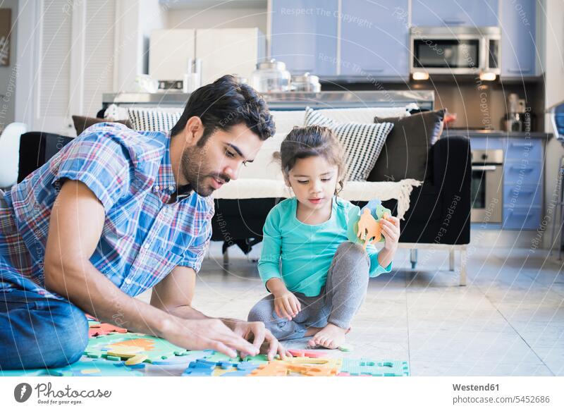 Father and daughter sitting on floor playing with children's puzzle daughters jigsaw puzzle father pa fathers daddy dads papa learning family families people