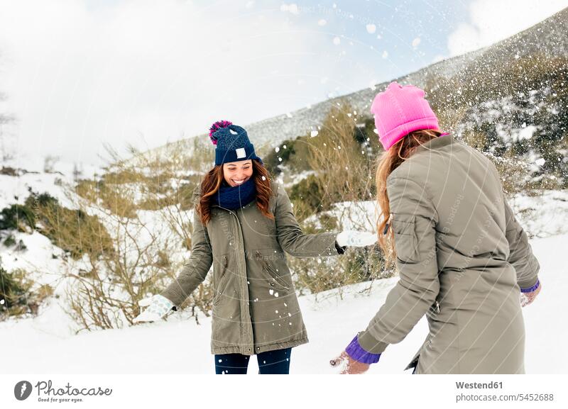 Two friends having fun in the snow friendship laughing Laughter throwing female friends winter hibernal positive Emotion Feeling Feelings Sentiments Emotions