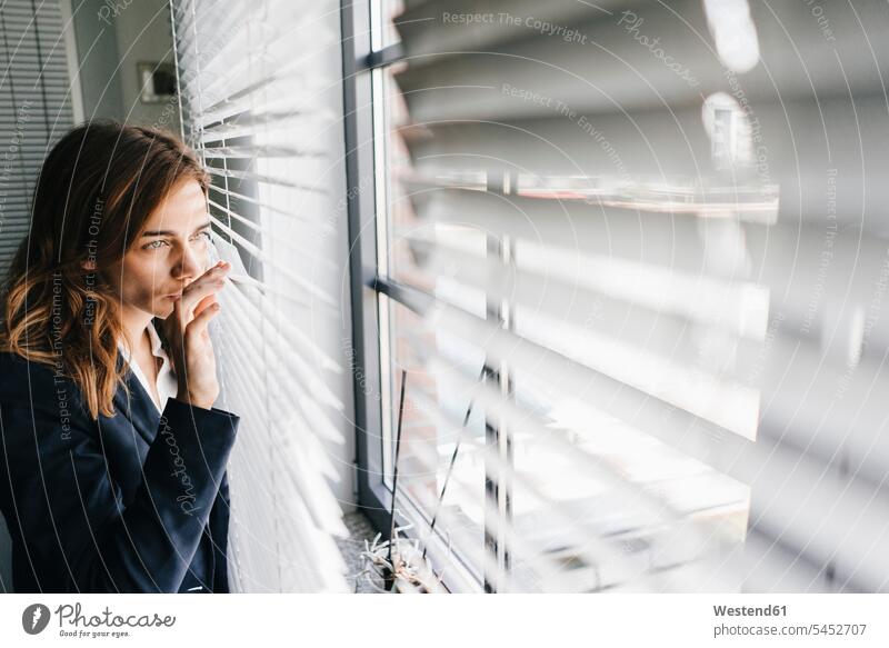 Woman standing by window, spying through blinds secret Secretive businesswoman businesswomen business woman business women roller blind roller blinds Monitoring