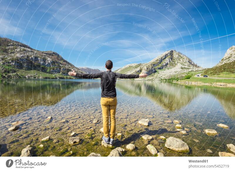 Spain, Asturias, Picos de Europa National Park, man standing with raised arms at Lakes of Covadonga happiness happy hiker wanderers hikers hiking nature