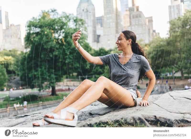 USA, Manhattan, smiling young woman taking selfie with smartphone in Central Park Smartphone iPhone Smartphones females women Selfie Selfies mobile phone