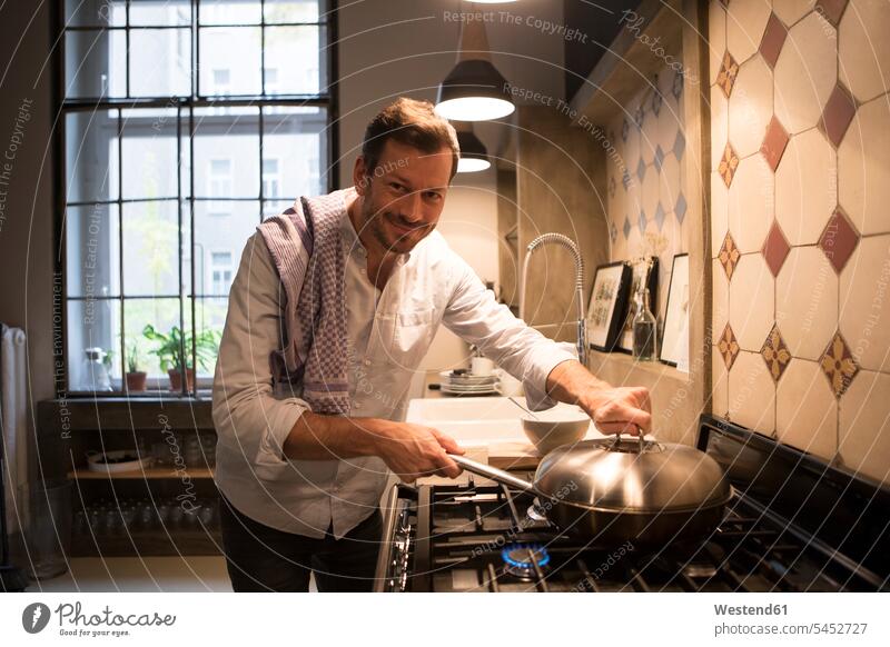 Portrait of smiling man cooking at home kitchen domestic kitchen kitchens men males Adults grown-ups grownups adult people persons human being humans