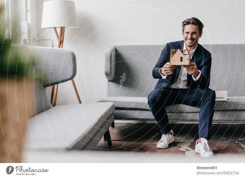 Smiling architect on couch holding architectural model models smiling smile man men males architects Adults grown-ups grownups adult people persons human being