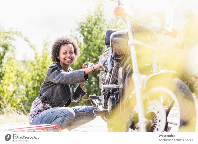 Young woman cleaning her motorcycle smiling smile cleanse cleansing motorbike Motor Cycle females women motor vehicle road vehicle road vehicles motor vehicles