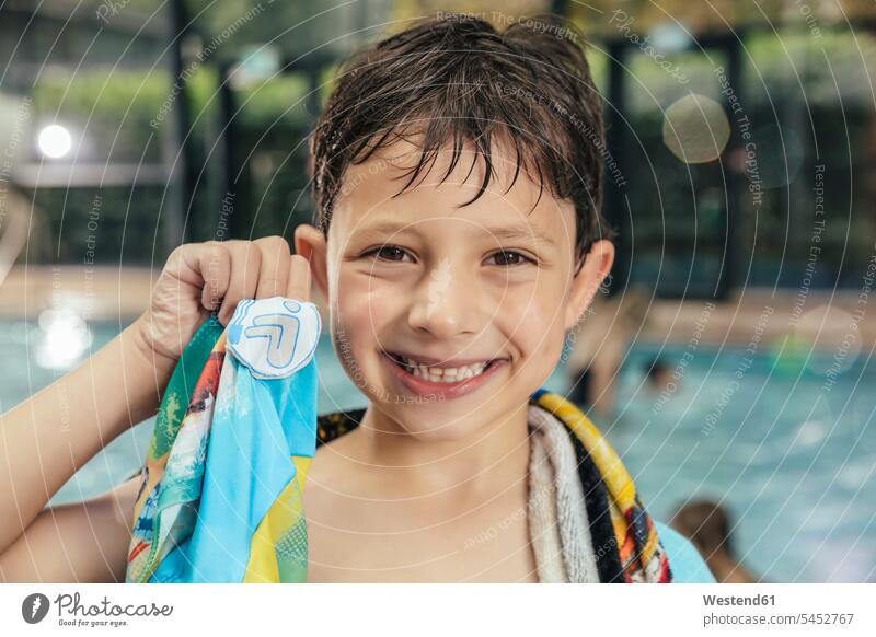 Portrait of proud boy showing his swimming badge at the poolside of an indoor swimming pool swimming bath Pride being proud smiling smile portrait portraits