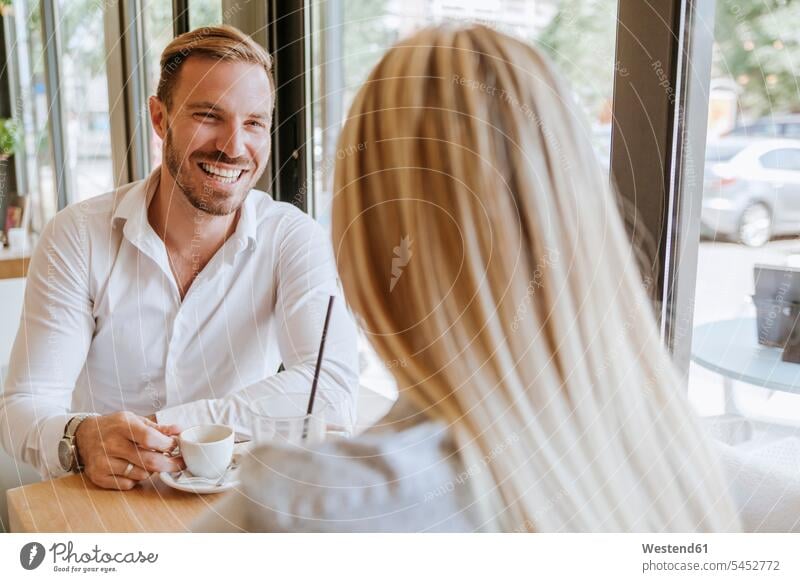 Happy man looking at woman in a cafe couple twosomes partnership couples talking speaking laughing Laughter people persons human being humans human beings