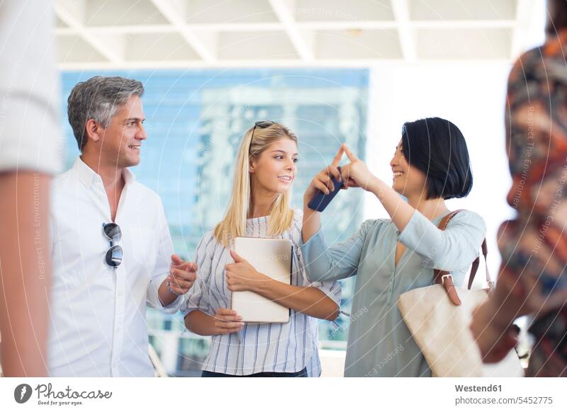 Group of casual businesspeople socializing on urban square mobile phone mobiles mobile phones Cellphone cell phone cell phones colleagues smiling smile