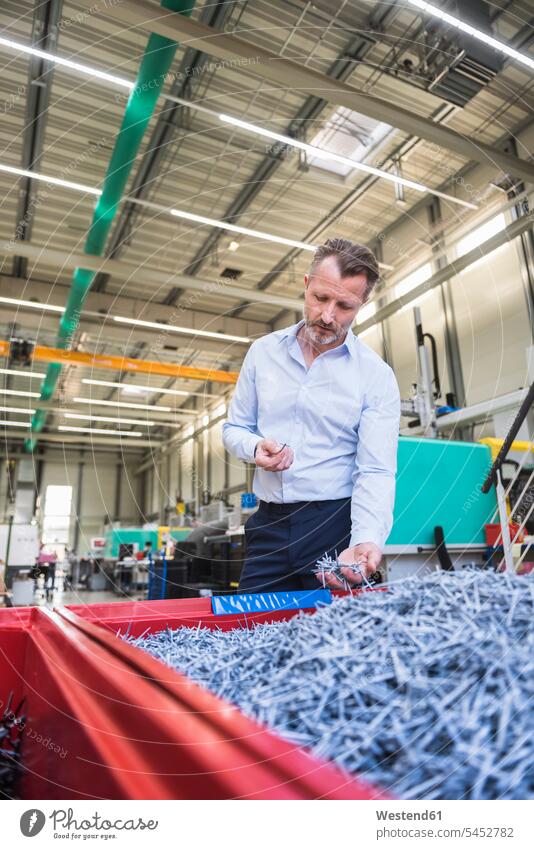Man in factory examining shred in container man men males Businessman Business man Businessmen Business men factories Adults grown-ups grownups adult people