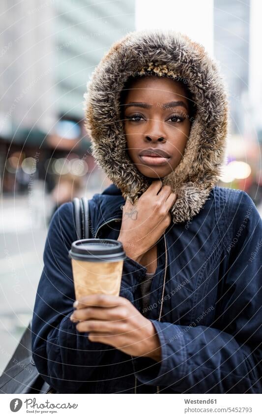 Portrait of fashionable young woman with coffee to go wearing hooded jacket serious earnest Seriousness austere Hooded Jackets Coffee to Go takeaway coffee