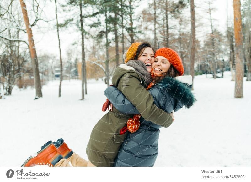 Two best friends having fun in the snow embracing embrace Embracement hug hugging female friends mate friendship happiness happy winter hibernal portrait