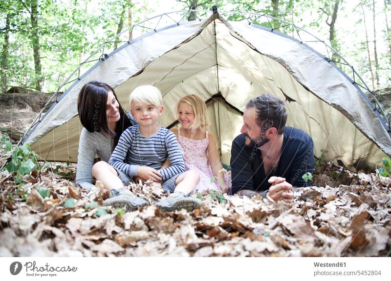 Happy family with tent in forest woods forests tents families smiling smile people persons human being humans human beings Quality Time daughter daughters