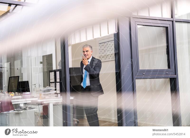 Mature businessman in office using smartphone Businessman Business man Businessmen Business men standing on the phone call telephoning On The Telephone calling