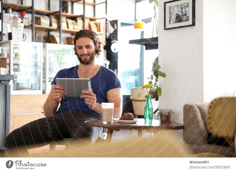 Portrait of young man sitting in a coffee shop using tablet cafe digitizer Tablet Computer Tablet PC Tablet Computers iPad Digital Tablet digital tablets