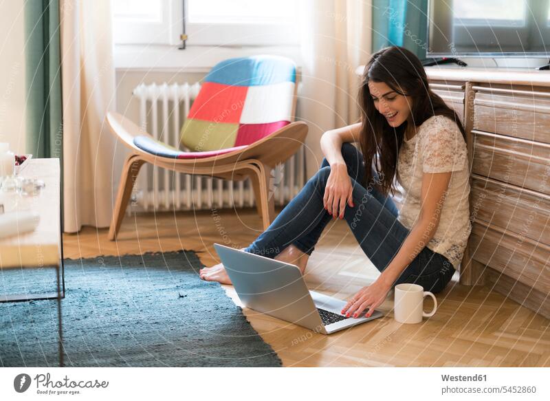 Young woman sitting on the floor at home using laptop Laptop Computers laptops notebook females women computer computers Adults grown-ups grownups adult people