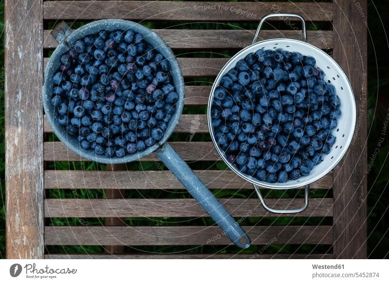 Colander and saucepan of blueberries on garden table Saucepan Saucepans nobody blueberry bilberry bilberries wooden large group of objects many objects plenty