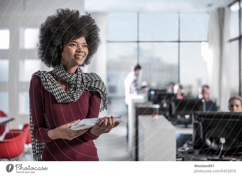 Smiling woman holding documents in office offices office room office rooms smiling smile females women workplace work place place of work Adults grown-ups