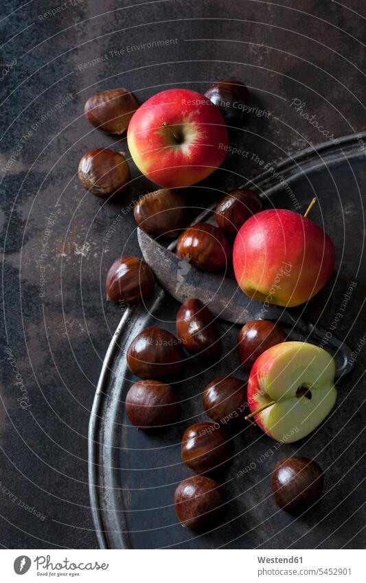 Sliced and whole apples, sweet chestnuts and an old knife on rusty background knives healthy eating nutrition wrought iron wrought-iron large group of objects