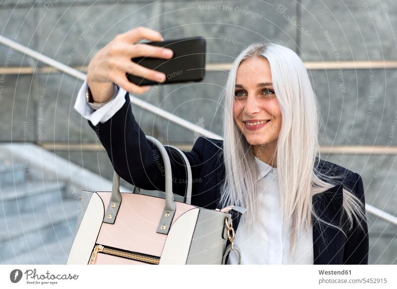 Smiling young woman ctaking a selfie on stairs in the city Selfie Selfies females women mobile phone mobiles mobile phones Cellphone cell phone cell phones