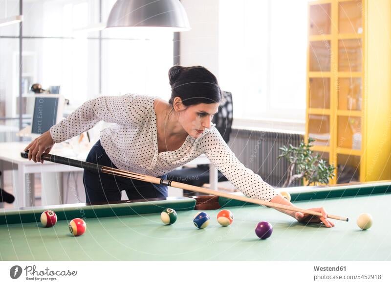 Determined businesswoman playing pool billard in modern office offices office room office rooms businesswomen business woman business women billiard table