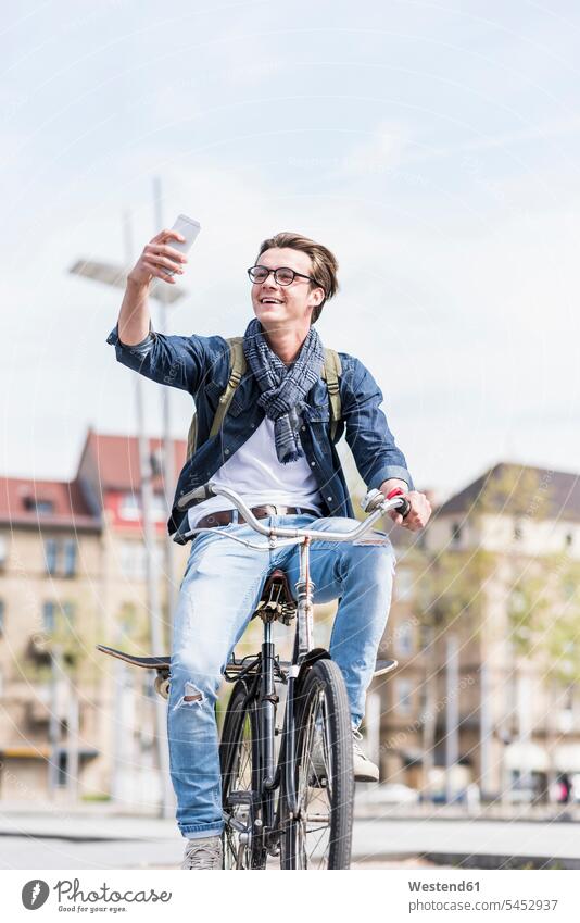 Young man with bicycle in the city using cell phone bikes bicycles mobile phone mobiles mobile phones Cellphone cell phones happiness happy driving drive men