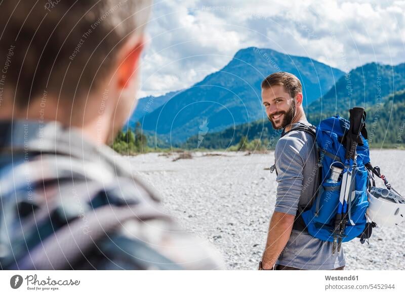 Germany, Bavaria, portrait of young hiker with backpack looking at his friend portraits friends wanderers hikers friendship hiking rucksacks backpacks