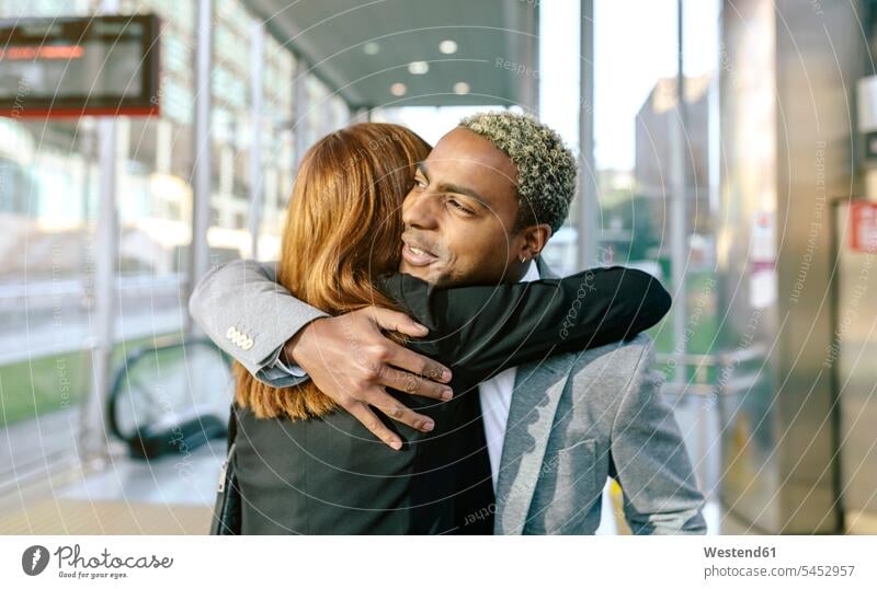 Young businessman and woman embracing at metro station business people businesspeople Farewell Farewells Good-Bye Goodbye colleagues embrace Embracement hug
