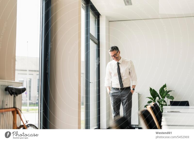 Laughing businessman standing in conference room Businessman Business man Businessmen Business men business people businesspeople business world business life