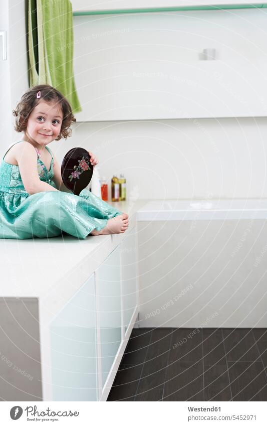 Portrait of smiling little girl with hand mirror sitting in bathroom females girls portrait portraits child children kid kids people persons human being humans
