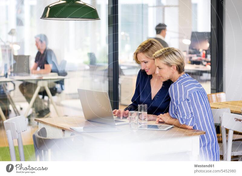 Two businesswomen sharing laptop businesswoman business woman business women smiling smile Laptop Computers laptops notebook Female Colleague business people