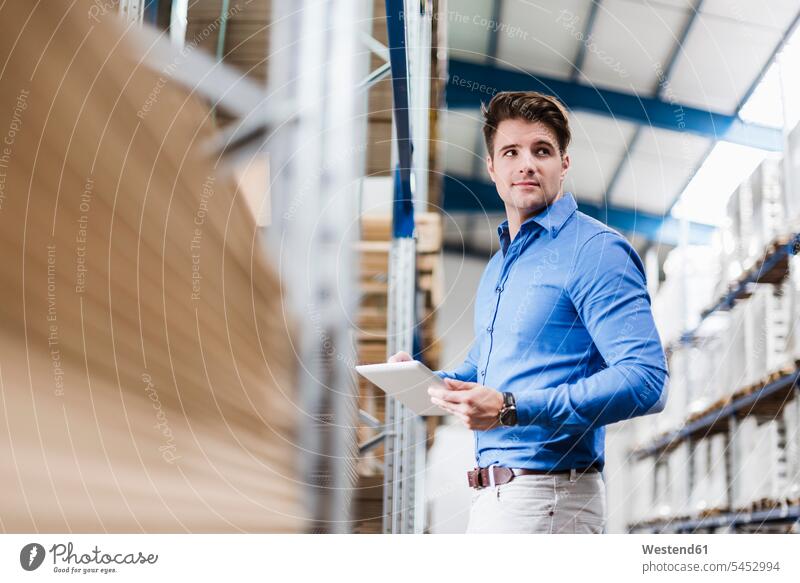 Young man working in warehouse, using digital tablet young man young men Businessman Business man Businessmen Business men standing factory employee clerk