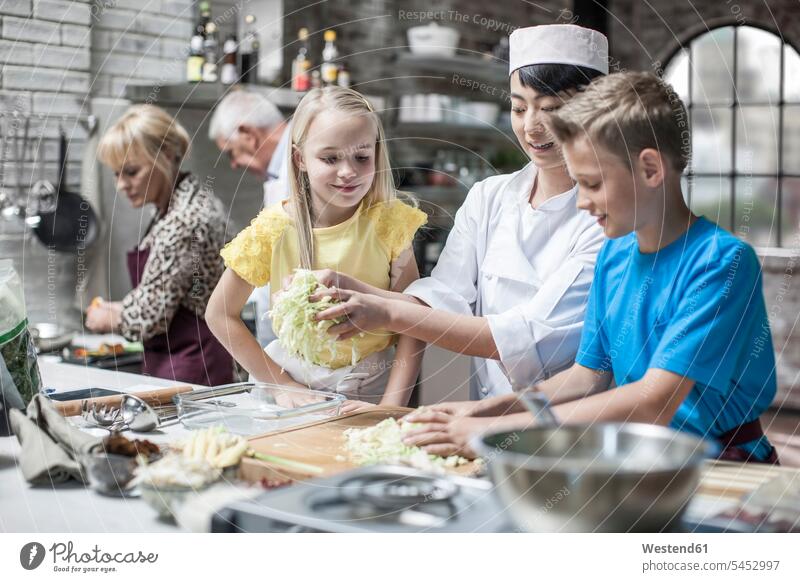 Female chef instructing kids in cooking class kitchen female cook group of people Group groups of people cooks Chefs persons human being humans human beings