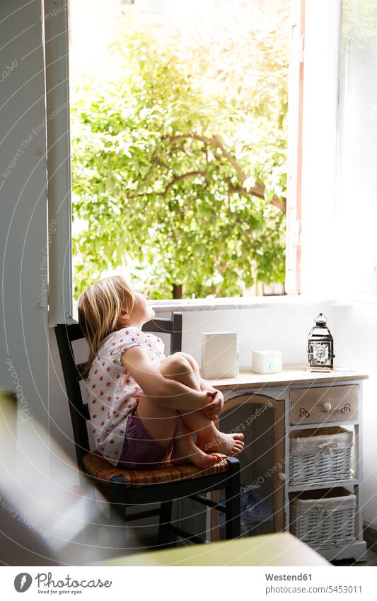 Little girl sitting on chair looking out of window females girls child children kid kids people persons human being humans human beings watching observing